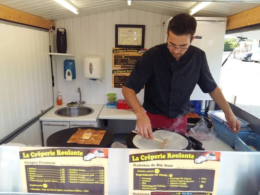 Arnaud Moalic cuit une galette sur la billig, devant les invités