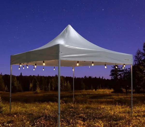 Guirlande lumineuse à ampoules suspendue sous un barnum blanc, de nuit