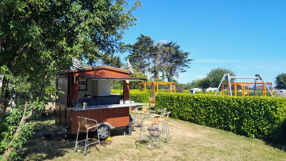 Roulotte à crêpes installée sur la pelouse d'un camping, près d'une aire de jeux