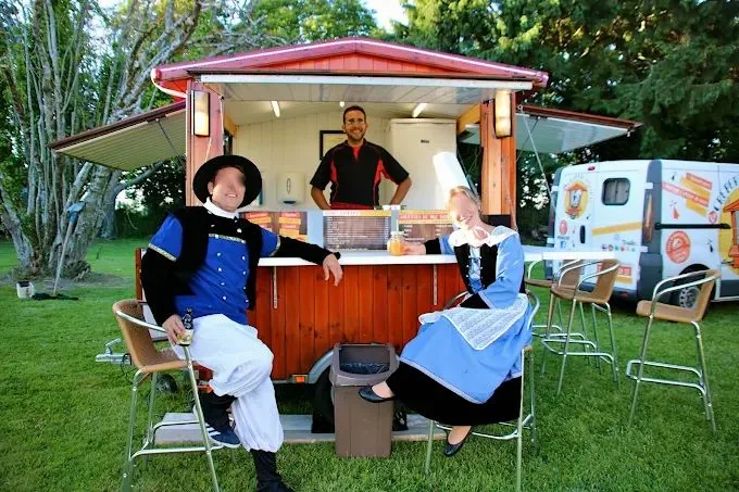 Roulotte en bois de La Crêperie Roulante, le food truck à crêpes, avec Arnaud Moalic au comptoir et deux invités en costume traditionnel breton