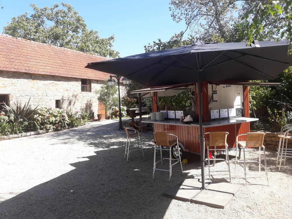 Roulotte à crêpes sous un grand parasol, dans la cour d'une maison en pierre