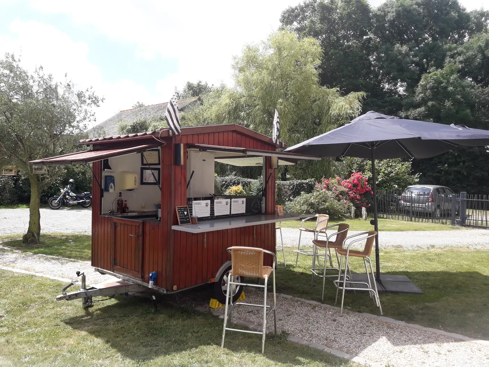 Roulotte à crêpes et parasols installés dans un jardin pour une réception