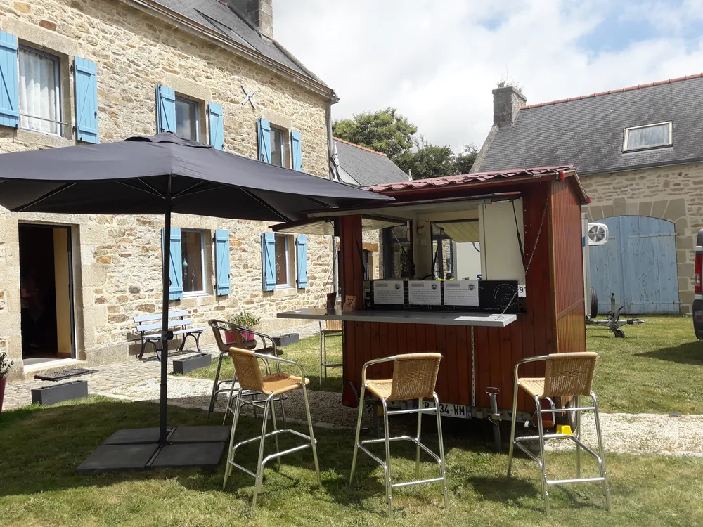 Roulotte à crêpes installée devant une maison en pierre aux volets bleus