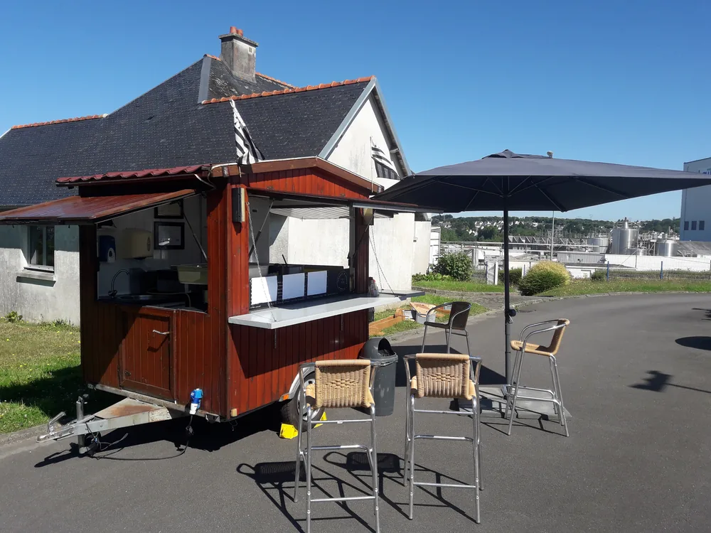 Roulotte à crêpes et parasol sur un parking, la mer en arrière-plan