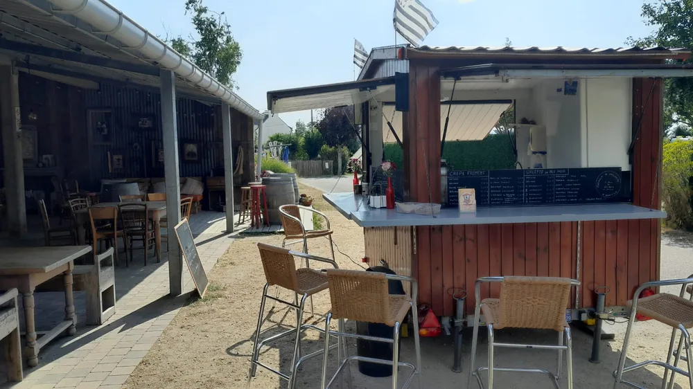 Roulotte à crêpes installée sous une terrasse couverte, tabourets hauts au comptoir
