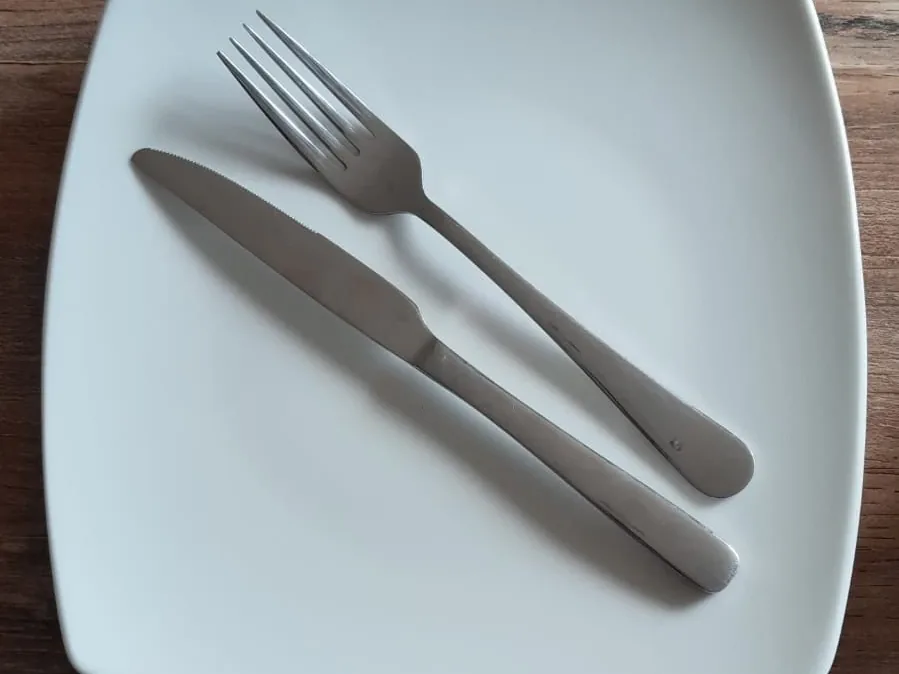 Assiette carrée écru avec fourchette et couteau en inox : la vaisselle de l'option